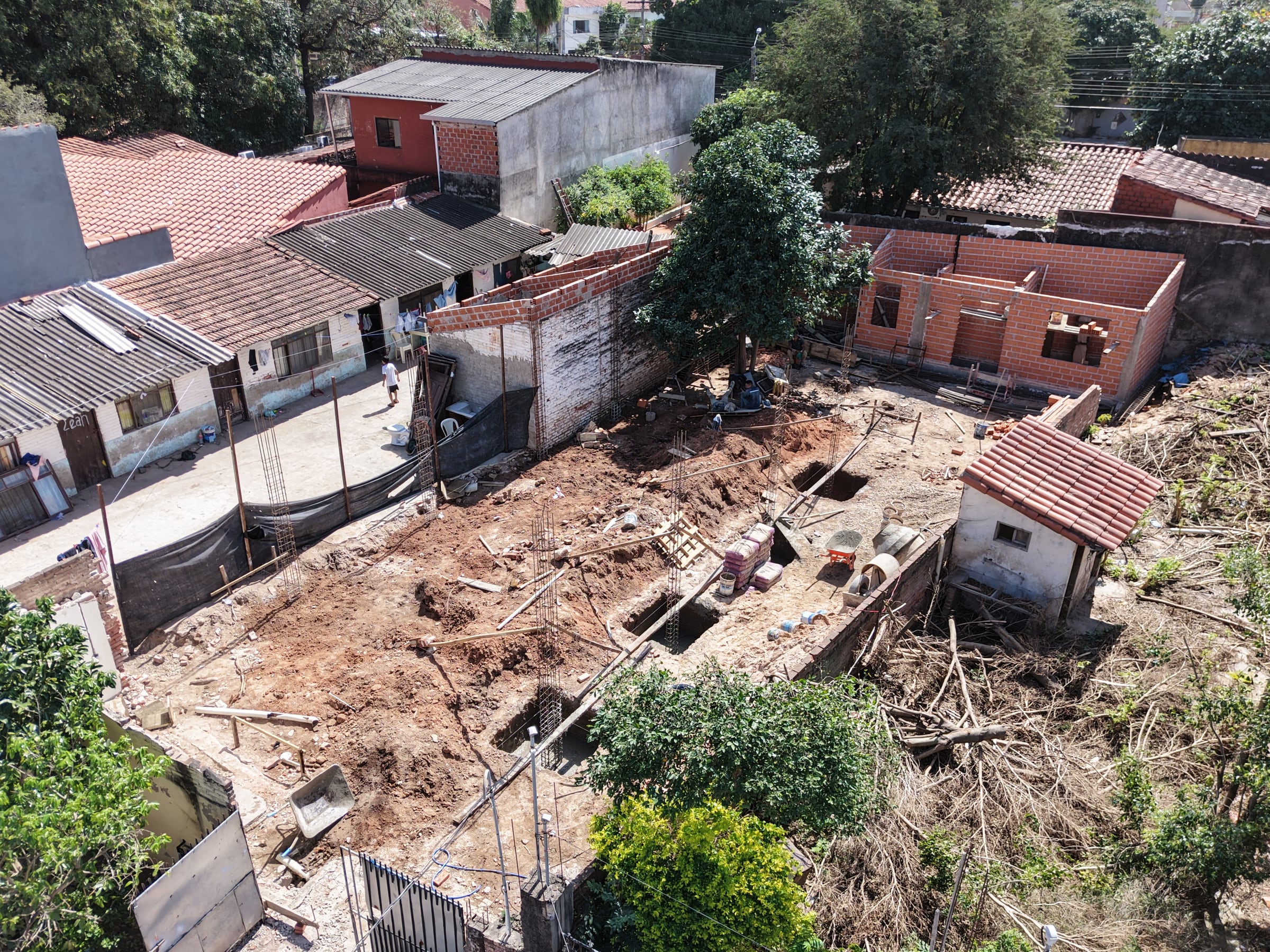 La obra desde otro ángulo, con la hormigonera, el material acopiado y las columnas en pie.