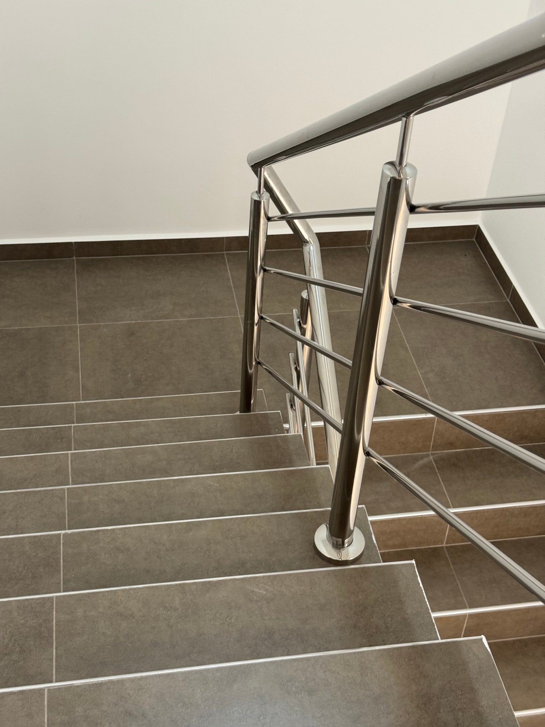 Detalle de peldaño de porcelanato y baranda de acero en la escalera.
