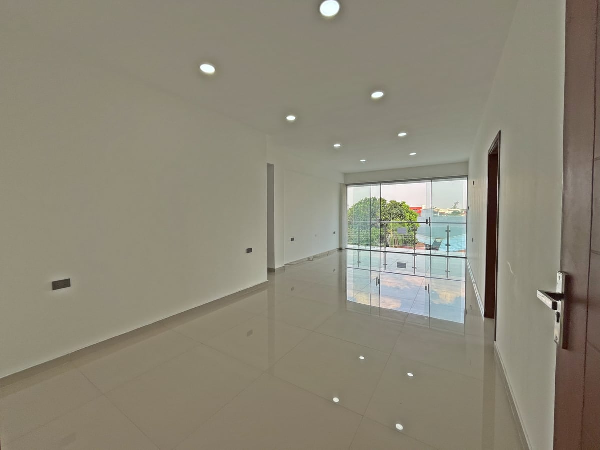 Sala–comedor del departamento de Casa Alicia: porcelanato y ventanal al balcón.
