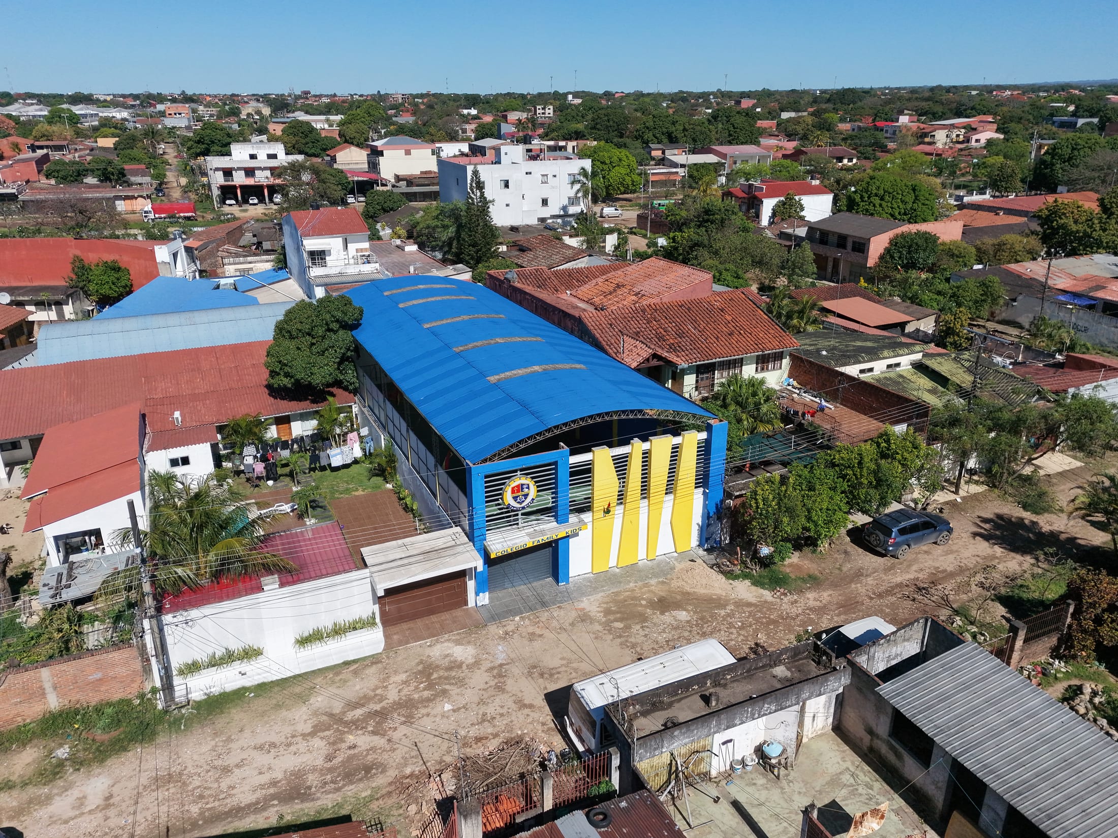 El conjunto del colegio en diagonal: la bóveda azul, el bloque de aulas y la fachada de aletas.