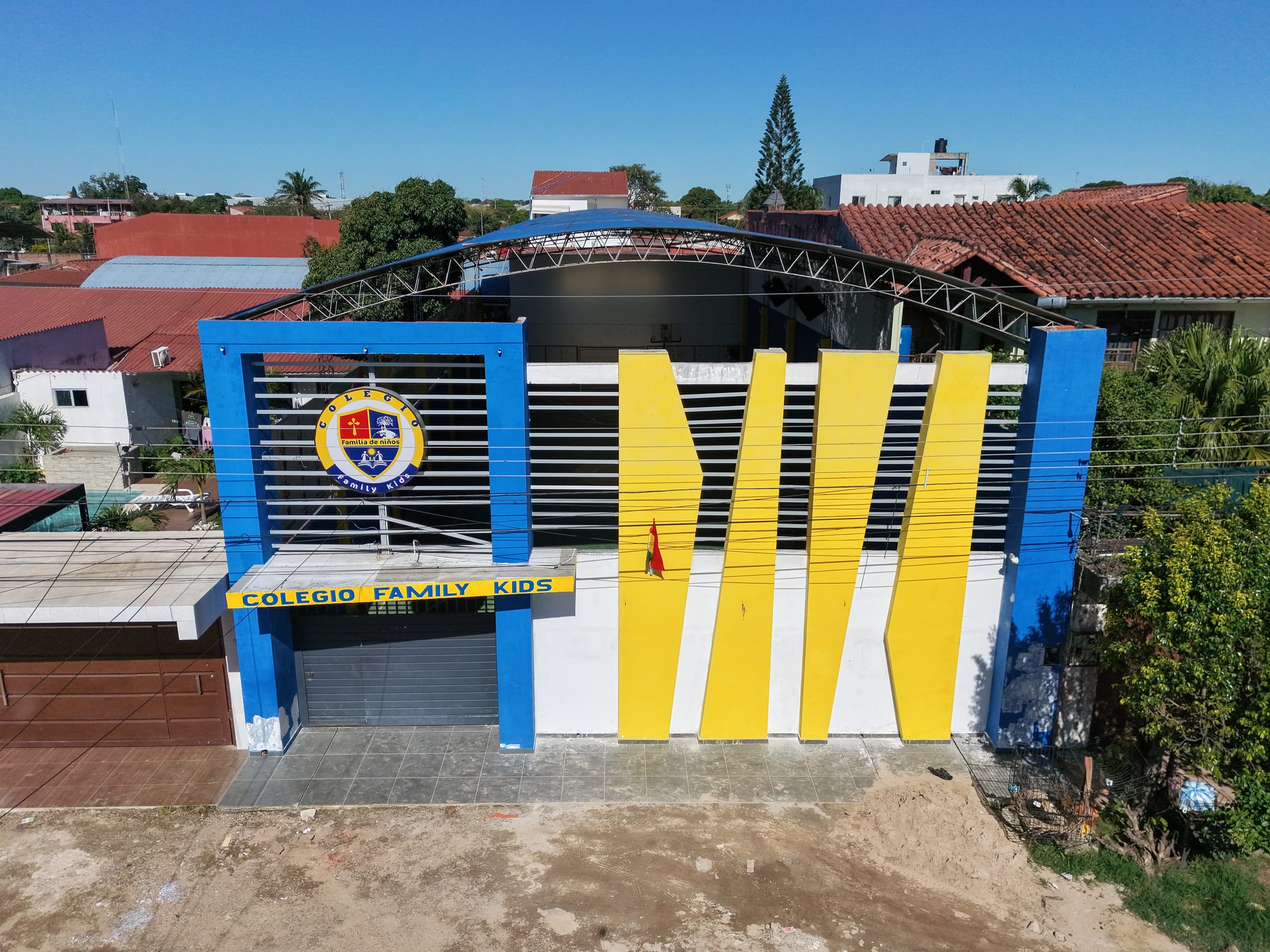 La fachada del Colegio Family Kids: pórtico azul, aletas amarillas y el escudo sobre la entrada.