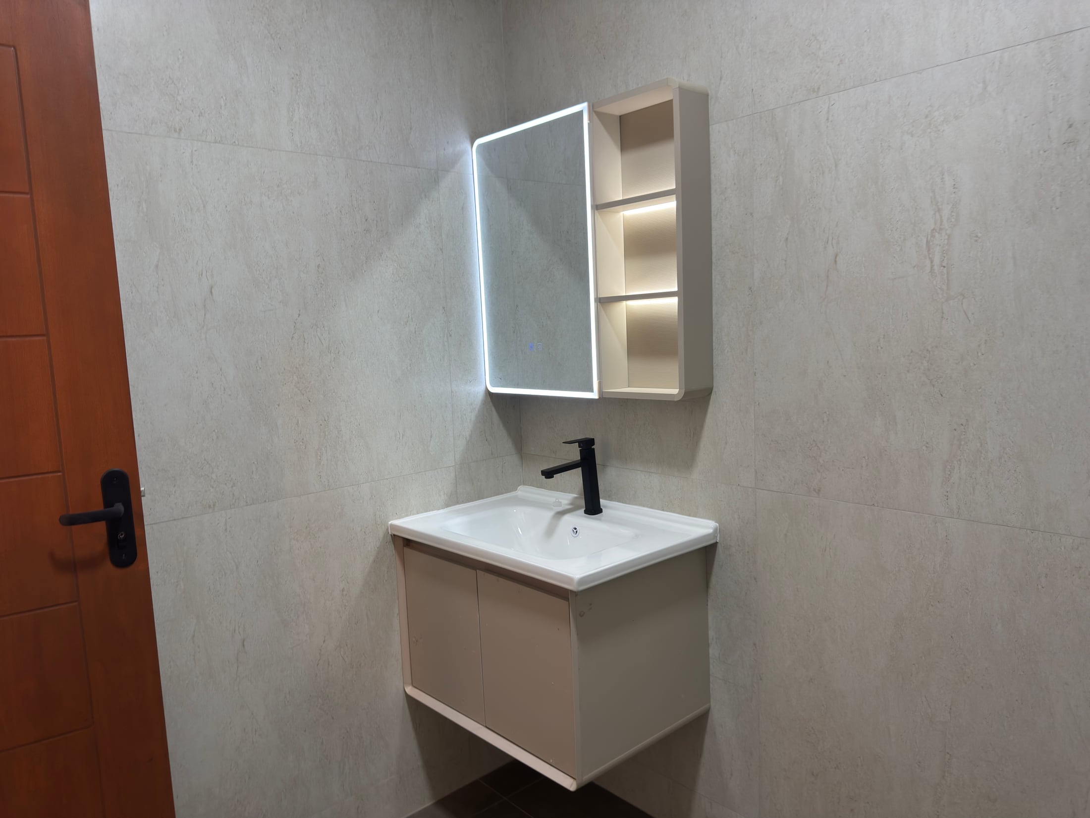 El baño compartido: mesón suspendido y espejo con estantes.