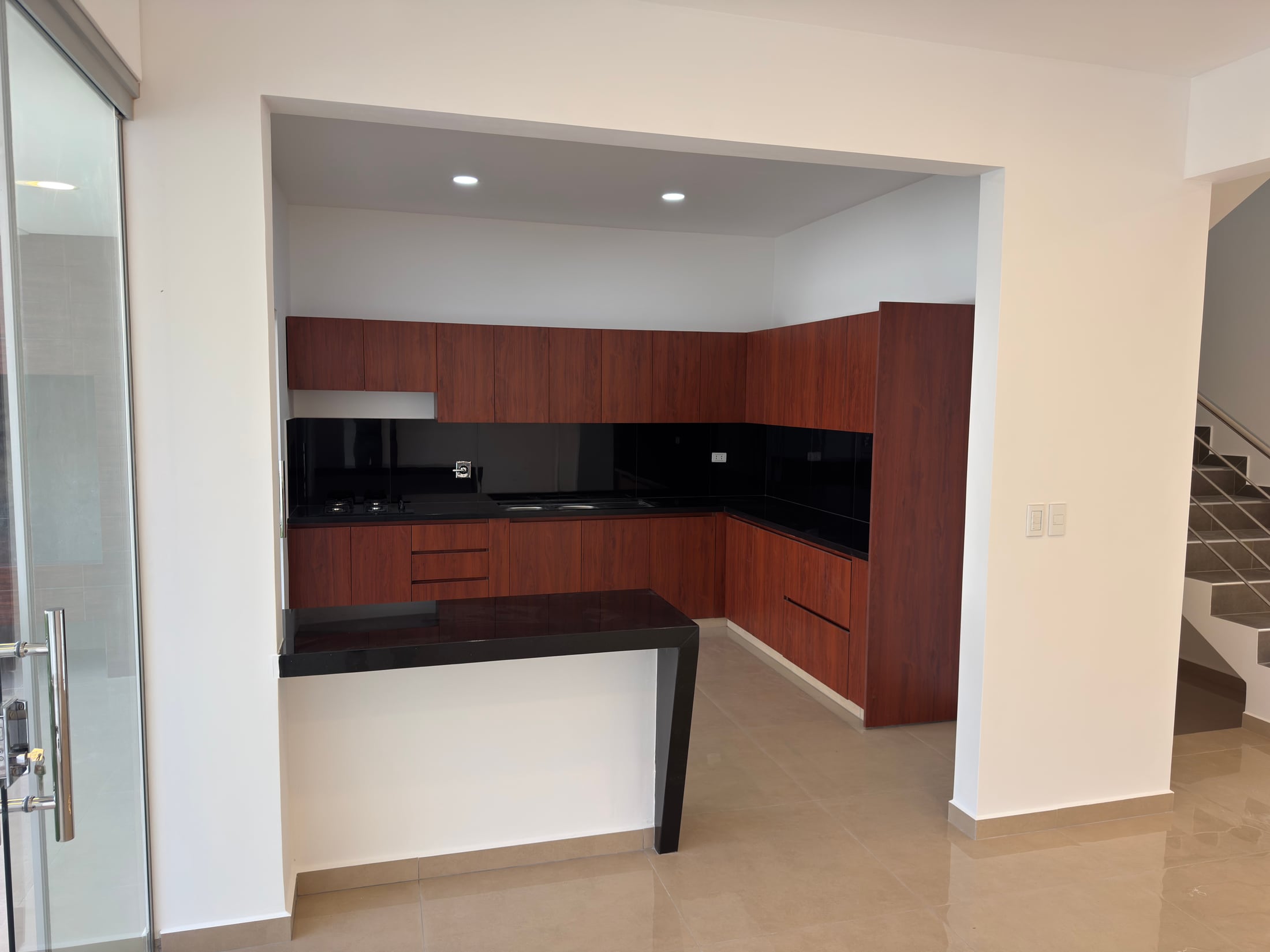 La cocina terminada: muebles de madera y mesón de granito negro.