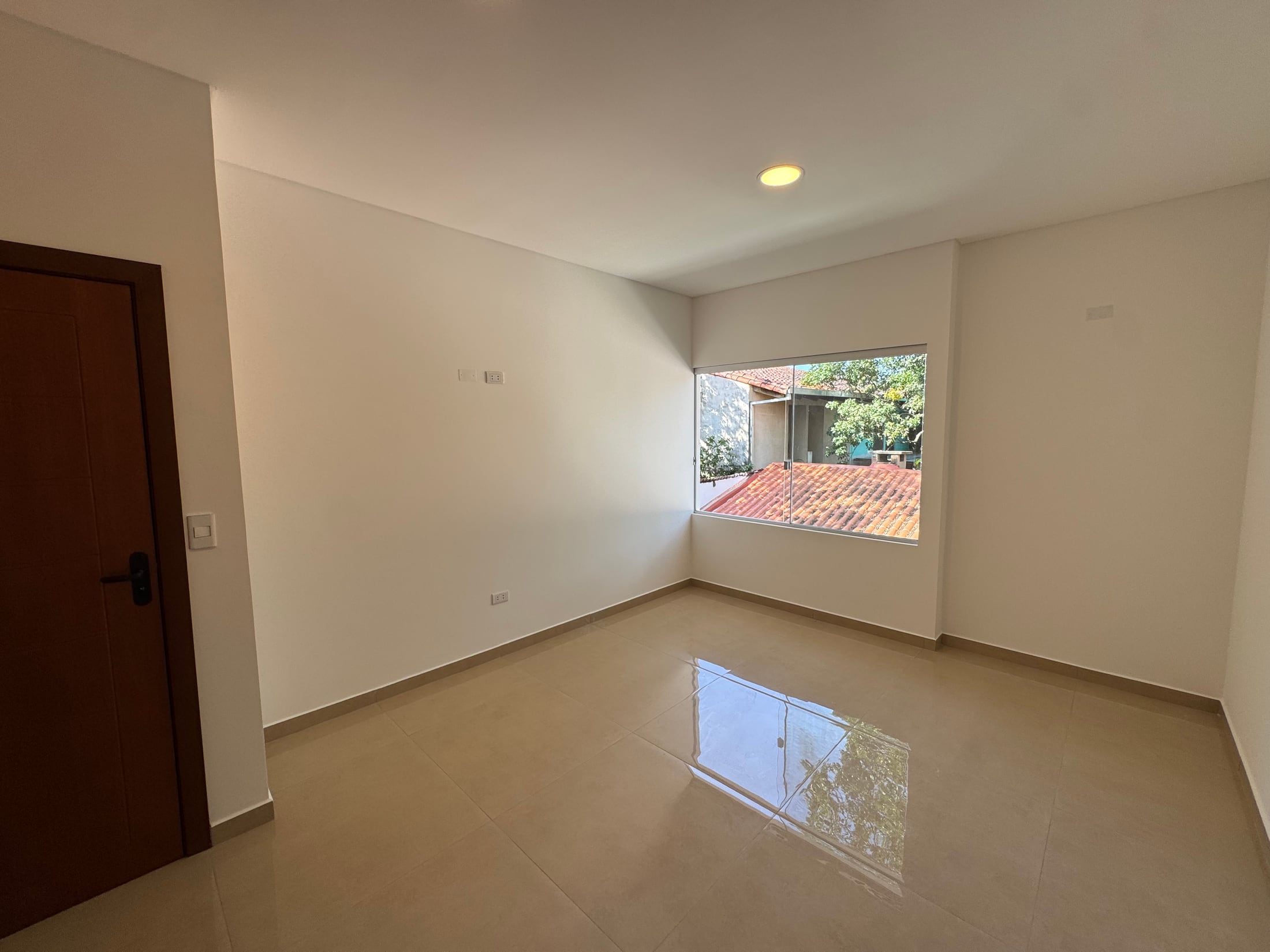 Un dormitorio vacío, con piso de porcelanato.