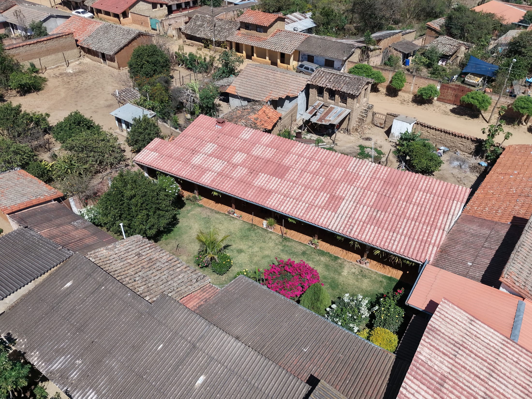 Vista aérea de la casa de campo de San Juan del Potrero: techo de teja, galería corrida y jardín con buganvilla.