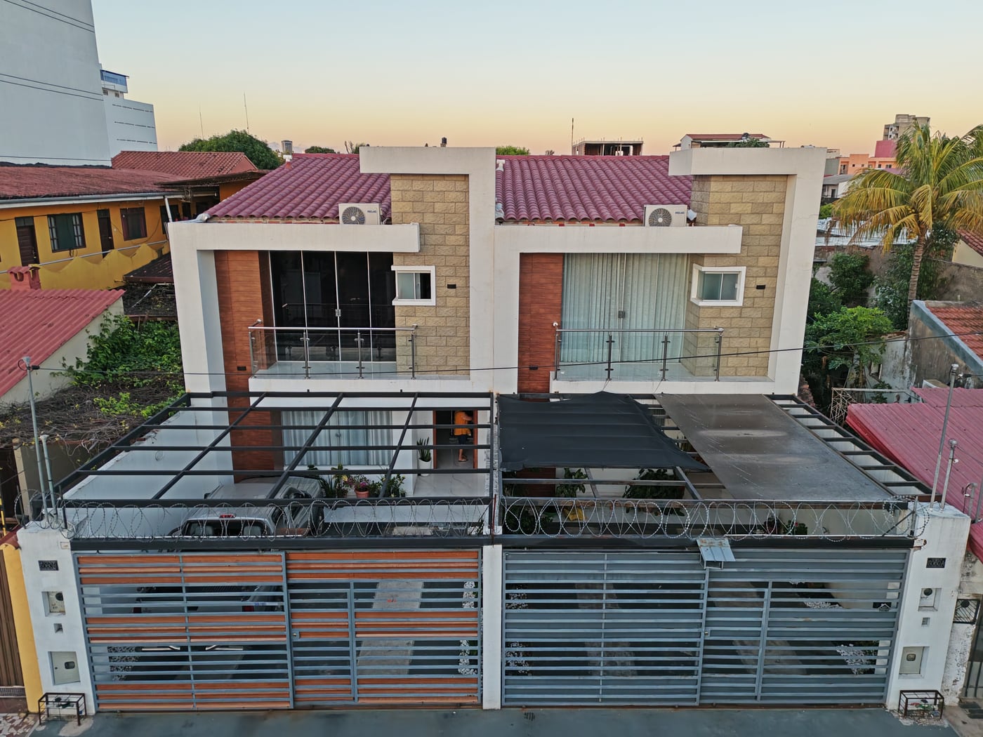 Las dos casas gemelas tipo B entregadas en Av. Centenario calle 6, vistas desde el frente al atardecer.