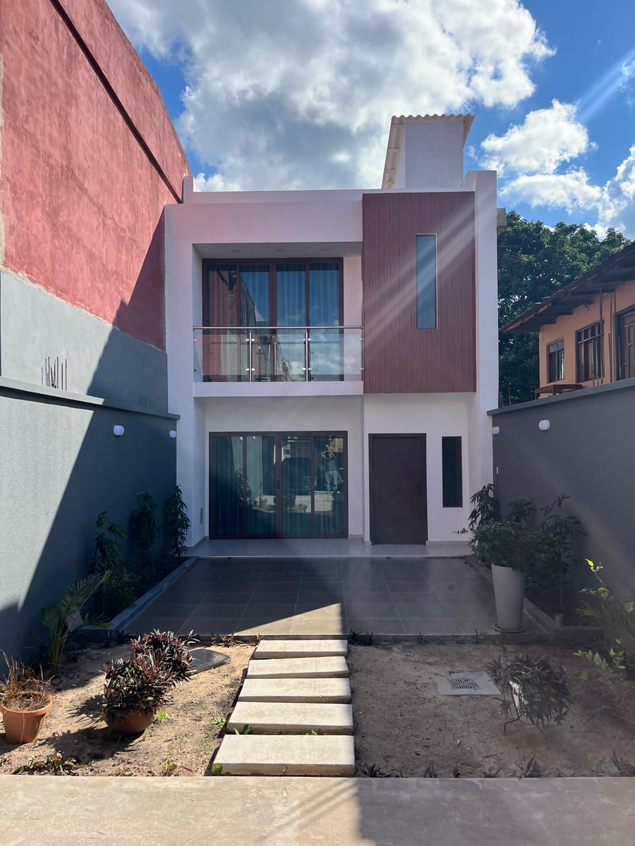 Entrada de la Casa Daniel, en Av. Centenario calle 5: revestimiento de madera, ventanal de vidrio y patio de porcelanato.
