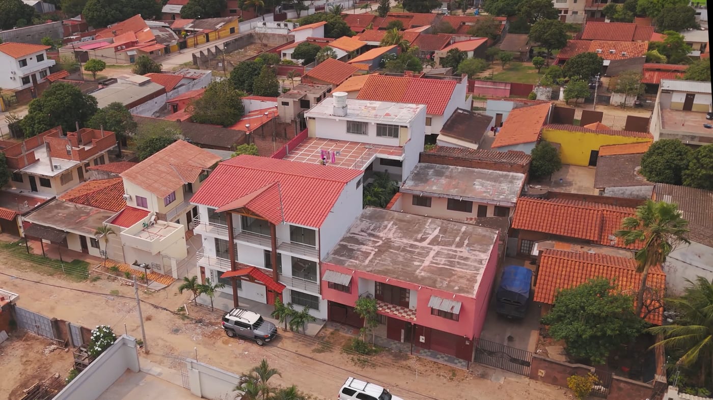 Vista aérea del edificio multifamiliar remodelado en Pampa de la Isla: tres plantas, techo de teja y balcones, entre las casas del barrio.
